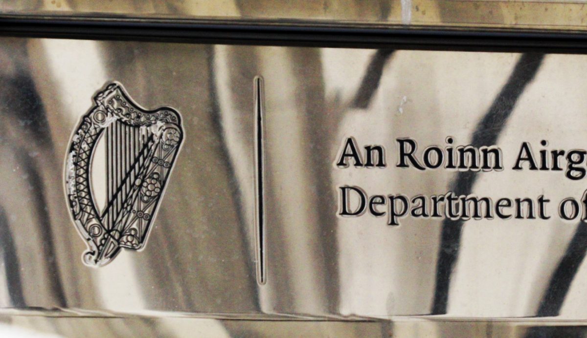 A photograph of a government department brass plaque. The image cuts off the latter half of plaque so the department will forever remain a mystery, unless you read the irish, can see "airg" and figure out it's the start of "airgeadais."