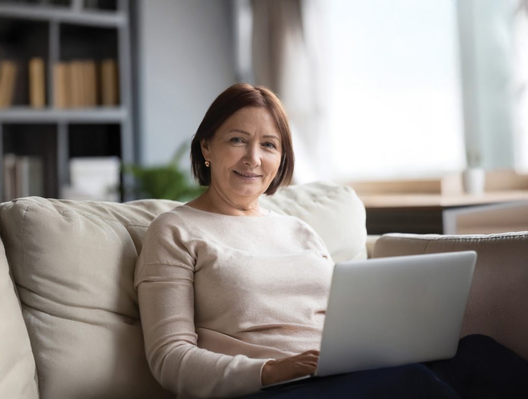 A woman sitting on a couch with a laptop, to represent retired members of Fórsa